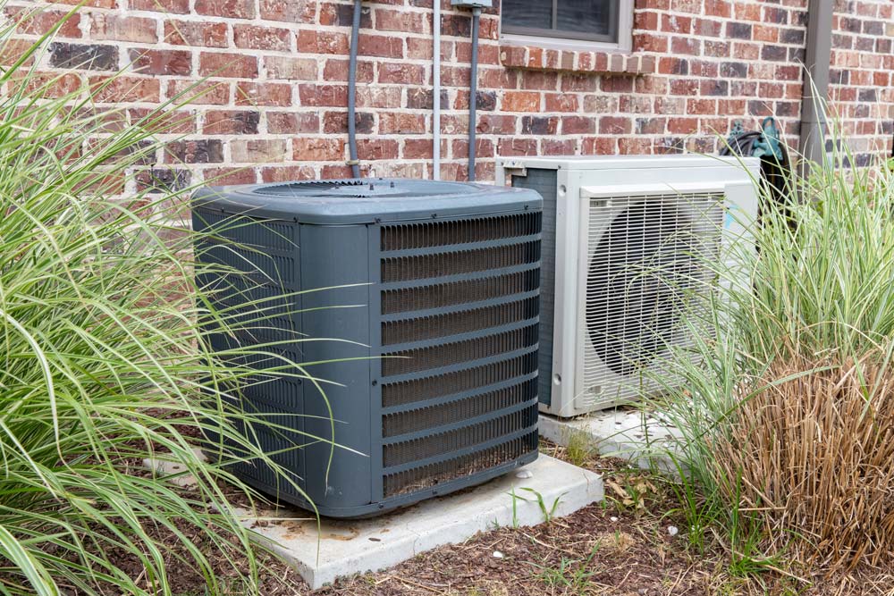 Outdoor HVAC units beside a brick house